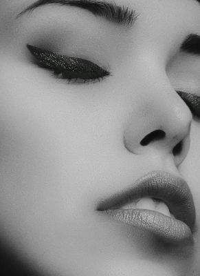 Artistic black and white close-up portrait of a woman's face with glamorous makeup.