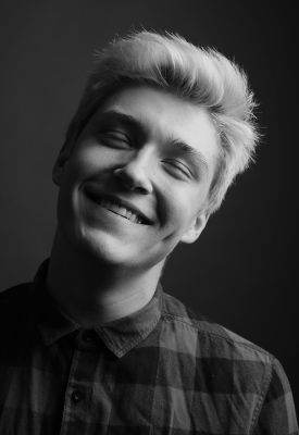 Grayscale portrait of a young man smiling warmly in a studio shot.
